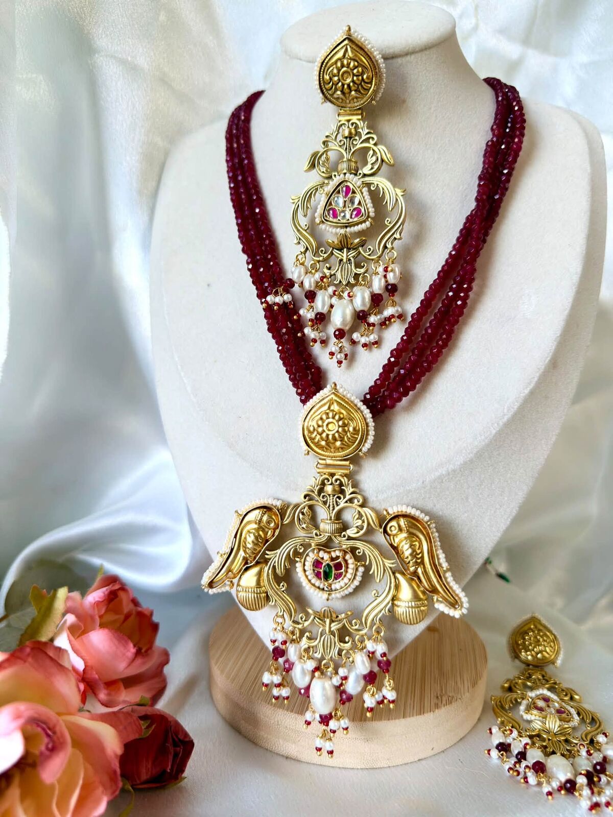 Gold and ruby bead necklace set displayed with flowers